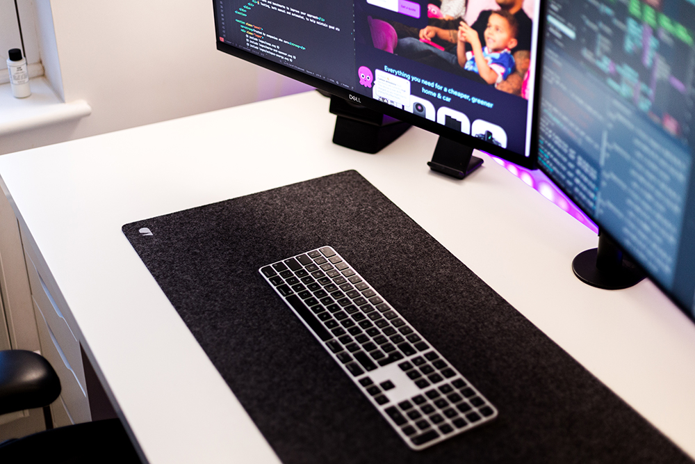 Close-up of the desk mat and keyboard - low profile and metallic. Purple lights are behind the desk